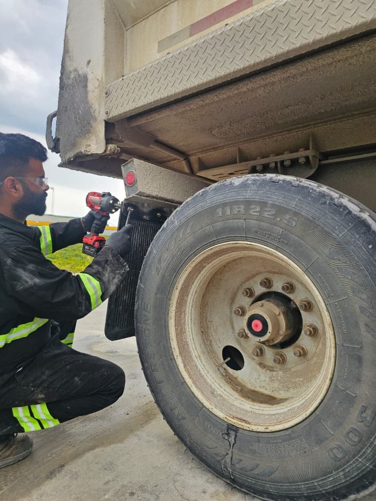 Hub Transport technician servicing a commercial trailer near the wheel and chassis